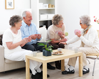 elderly woman playing cards with friends on couch