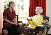 caregiver talking to elderly woman drinking tea